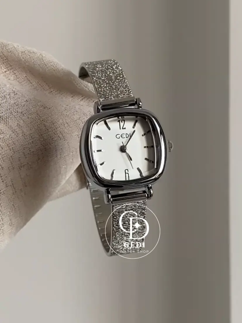 A delicate blend of modern elegance and vintage charm, this silver sparkle oval women's watch is designed to make a subtle yet striking statement. Featuring a polished oval case and a minimalist white dial, the design is elevated by a shimmering textured strap that catches the light beautifully with every movement.