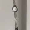 A delicate blend of modern elegance and vintage charm, this silver sparkle oval women's watch is designed to make a subtle yet striking statement. Featuring a polished oval case and a minimalist white dial, the design is elevated by a shimmering textured strap that catches the light beautifully with every movement.