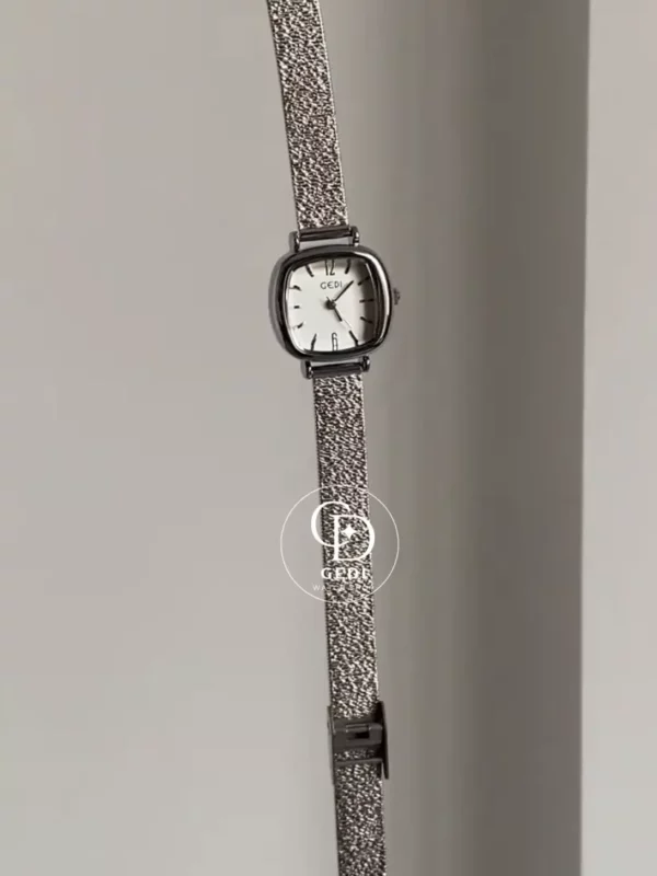 A delicate blend of modern elegance and vintage charm, this silver sparkle oval women's watch is designed to make a subtle yet striking statement. Featuring a polished oval case and a minimalist white dial, the design is elevated by a shimmering textured strap that catches the light beautifully with every movement.