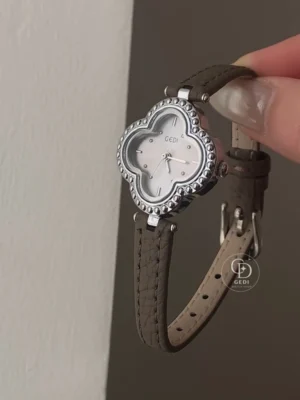 Bring a distinctive touch to your everyday style with this GEDI women's watch. A clover-shaped case with a decorative beaded border frames a softly shimmering dial, combining playful curves with classic elegance. The polished silver-tone finish contrasts beautifully with the slim, textured strap and its neat stitching. Simple hour markers keep the design balanced, making this watch an elegant finishing touch for relaxed outfits, office looks, or weekend occasions.